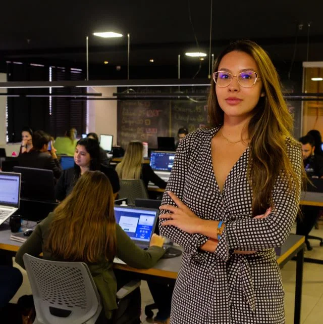 Luanna Silva no escritório da Pet Viajante com a equipe trabalhando ao fundo